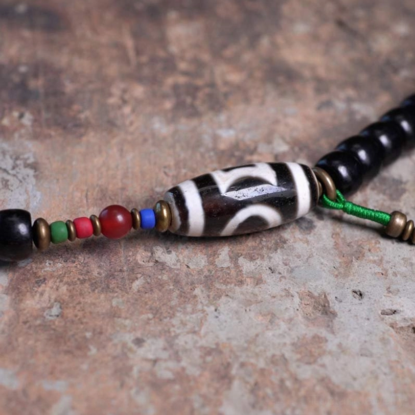Authentic hand-painted dzi bead detail on Tibetan 108-bead mala necklace showing intricate protective symbols