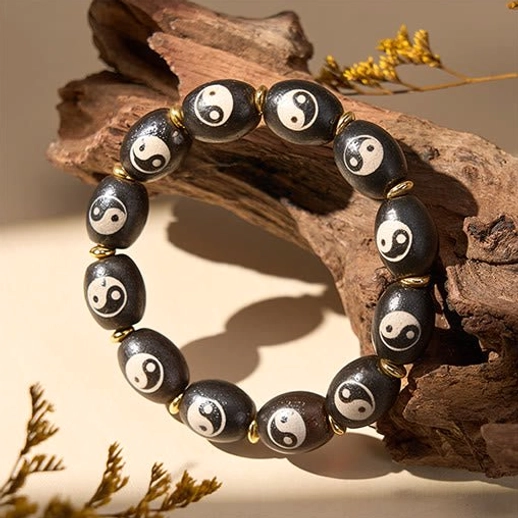 Hand-painted Tibetan Dzi Bead bracelet close-up highlighting intricate Yin Yang artistry, natural agate texture, and gold-tone metal accents