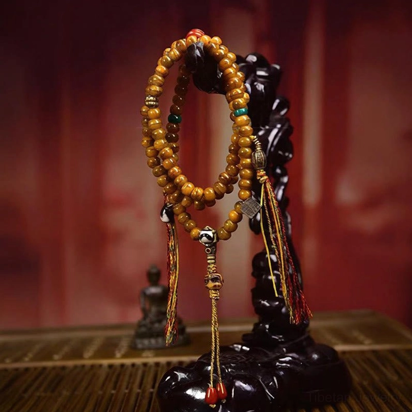 Hanging Tibetan mala prayer beads with red tassel and silver hardware on vintage backdrop - front view