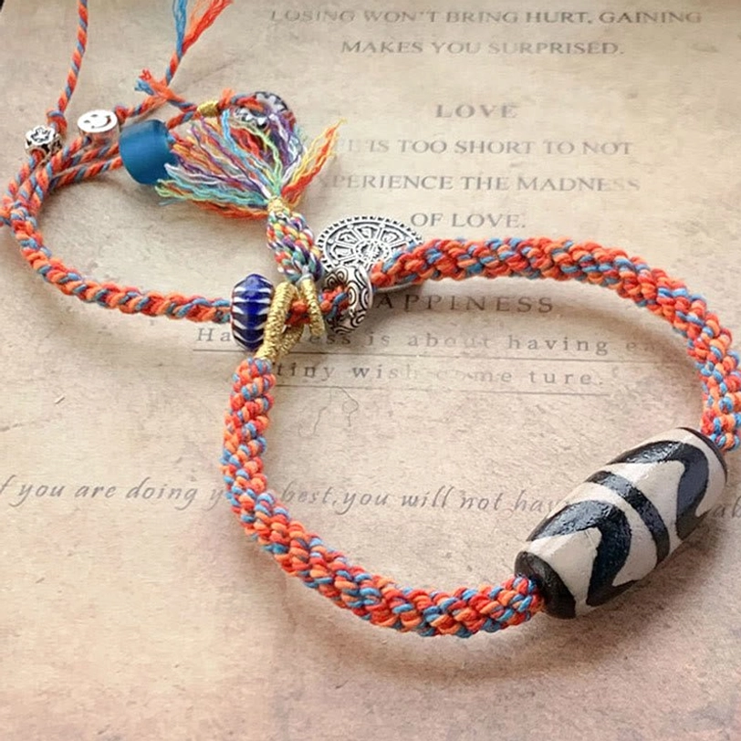 Red and blue Tibetan Nine-Eye Dzi bead bracelet with 925 sterling silver charm and blue accent bead on vintage paper