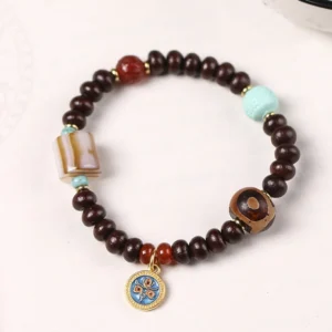 Tibetan Dzi bead bracelet featuring purple bodhi seeds, three-eye dzi amulet, red agate, and turquoise accent on white studio background