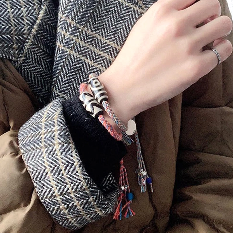 Woman wearing red Tibetan Dzi bead bracelet with silver charm on wrist, close-up side view