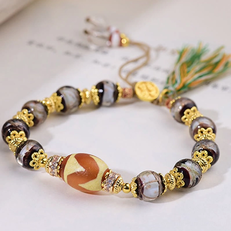 Liuli glass Dzi bead bracelet angled flat lay on book page background showing clear bead layout and gold hardware