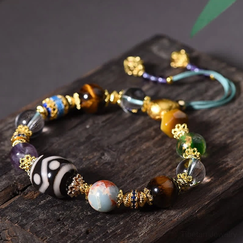 Tibetan Dzi bracelet flat lay with green leaf styling on wooden surface
