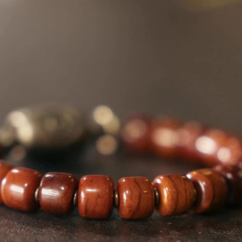 Macro photography of Tibetan bone Dzi bracelet detail showing wooden barrel beads, metal spacers and shallow depth focus effect