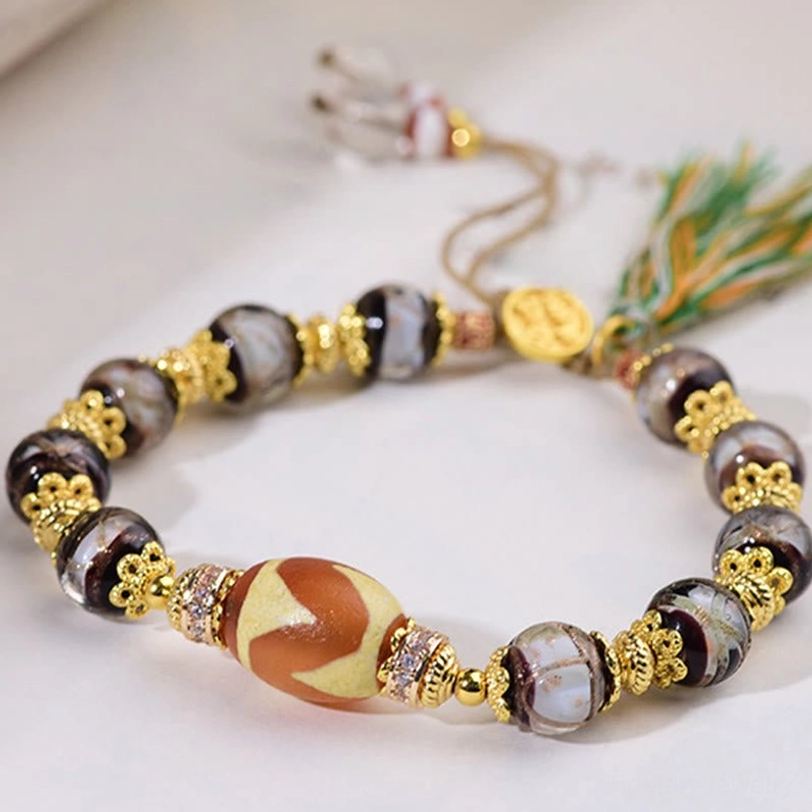 Three-quarter angle shot of Nine-Eye Dzi bead bracelet with round metal spacers and gold brand charm