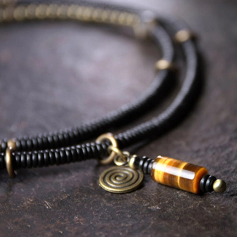 Close-up of Tibetan Dzi bead jewelry components showing hand-painted beads, bronze metal hardware, and pendant focus
