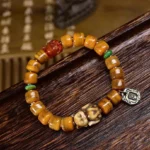 Tibetan dzi fox bone bead bracelet with copper charms flat lay on wooden surface