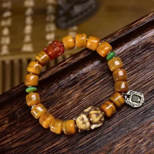 Tibetan dzi fox bone bead bracelet with copper charms flat lay on wooden surface
