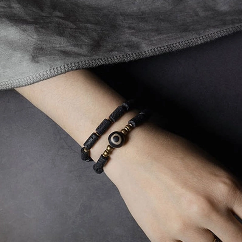 Single wrap lava rock dzi bracelet worn on wrist side view - showing three-eye dzi bead and brass hardware details