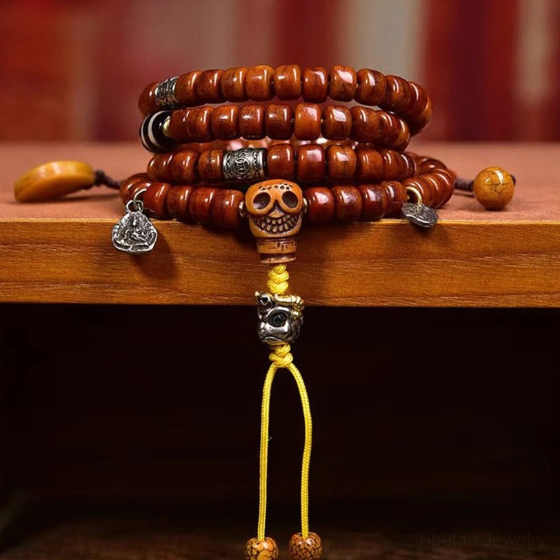 Eye-level close-up photograph of Tibetan dzi bead mala on wooden display shelf showing detailed bead texture and yellow tassel cord