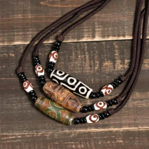 Collection of Tibetan nine-eye dzi bead necklaces in brown and black displayed on vintage wooden table - authentic protective amulet pendants