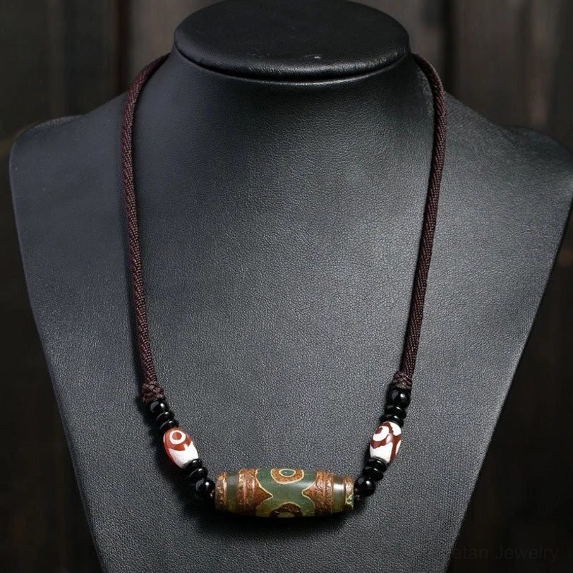 Tibetan green dzi bead necklace worn on mannequin with woven brown cord - authentic spiritual jewelry pendant display