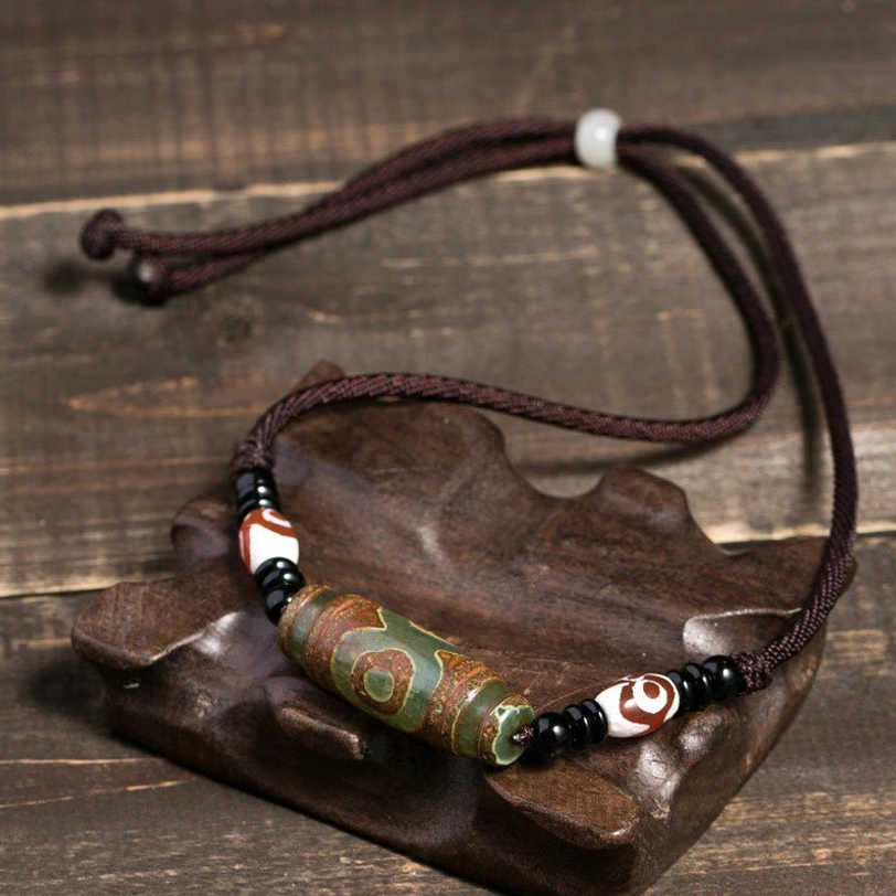 Green Tibetan dzi bead necklace on wooden display stand with brown adjustable cord - abundance and protection talisman