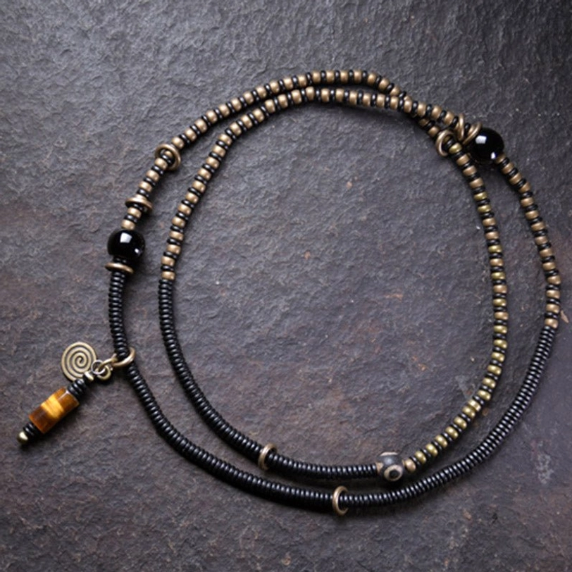 Layered Tibetan Dzi bead necklace with mixed black and bronze beads, copper hardware, and matching pendant set, top-down view