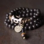 Tibetan Dzi bead ebony wood couples protection bracelet flat lay with nine-eye amulet and antique bronze hardware