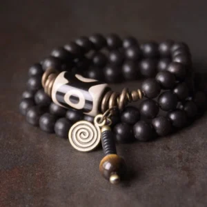 Tibetan Dzi bead ebony wood couples protection bracelet flat lay with nine-eye amulet and antique bronze hardware
