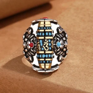 Authentic Tibetan rotating mantra ring top view showing dual Garuda carvings, central blue turquoise dzi bead with Om Sanskrit engravings