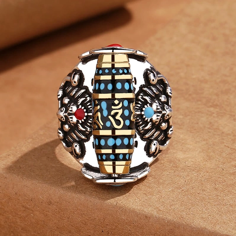 Authentic Tibetan rotating mantra ring top view showing dual Garuda carvings, central blue turquoise dzi bead with Om Sanskrit engravings