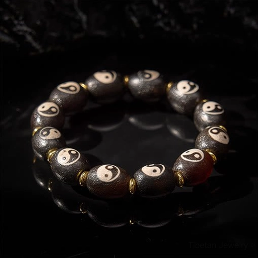 Top-down flat lay of Tibetan Dzi Bead bracelet with reddish-brown and dark brown agate showcasing hand-painted Yin Yang patterns and gold spacer beads