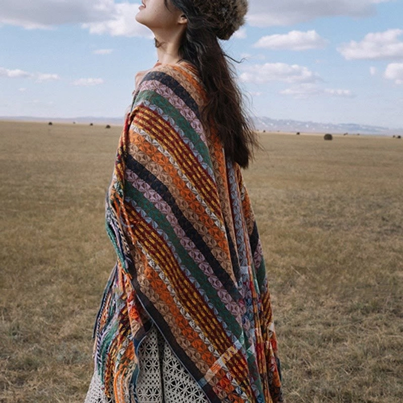 Rich earthy-colored Tibetan striped shawl with soft woven texture draped on body in wide open grassland outdoor setting