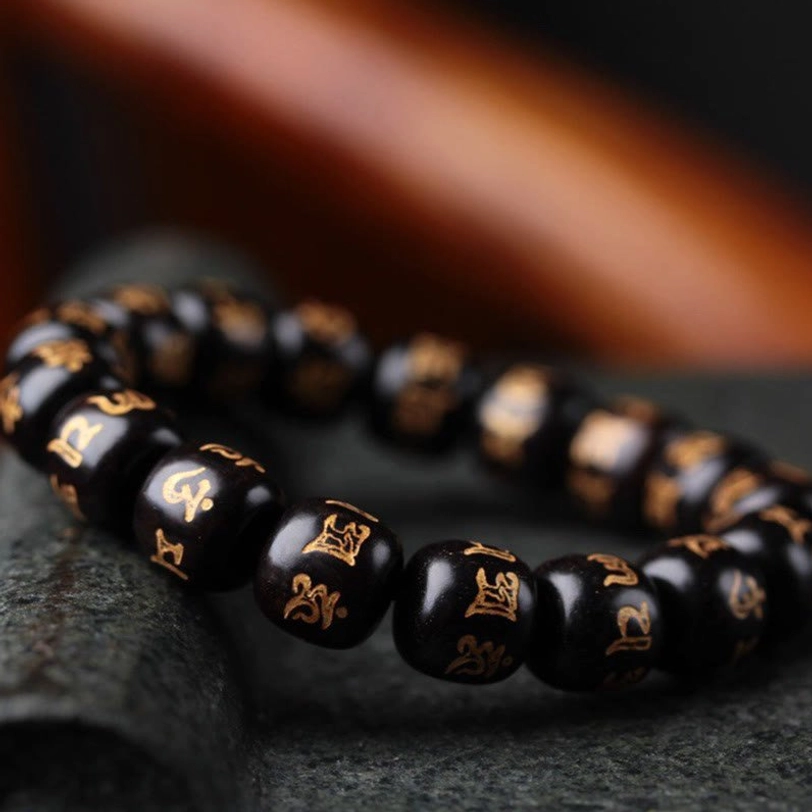 Side profile close-up of Om Mani Padme Hum ebony bracelet highlighting individual bead craftsmanship with clear golden sutra engravings