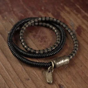 Tibetan ebony wood and copper bracelet flat lay with metal tag on wooden surface