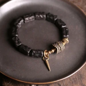 Handcrafted ebony and copper protection bracelet with hammered metal details displayed on dark metal plate
