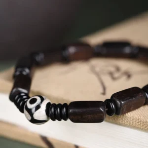 Close-up side view of Tibetan balance bracelet showing polished ebony beads and hand-painted Dzi bead detail