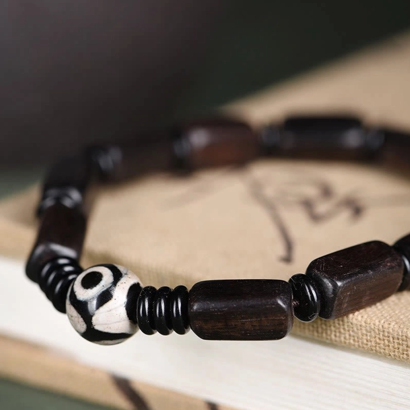 Close-up side view of Tibetan balance bracelet showing polished ebony beads and hand-painted Dzi bead detail