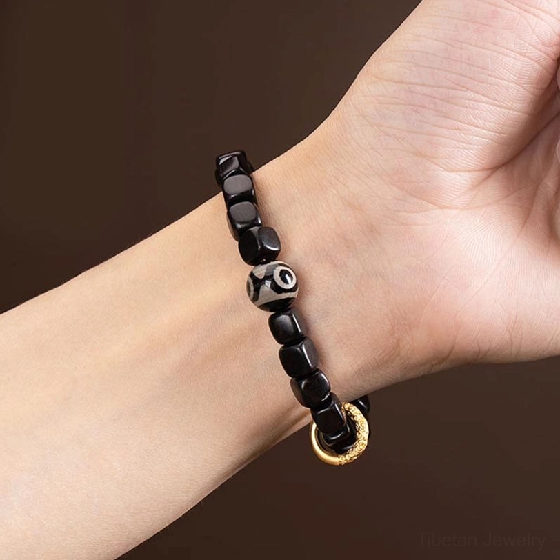 Worn tibetan ebony dzi bead bracelet on wrist demonstrating comfortable fit and spiritual amulet aesthetic