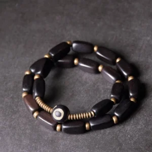 Tibetan ebony wood double wrap bracelet with round dzi bead and copper spacers, top-down full view on dark background