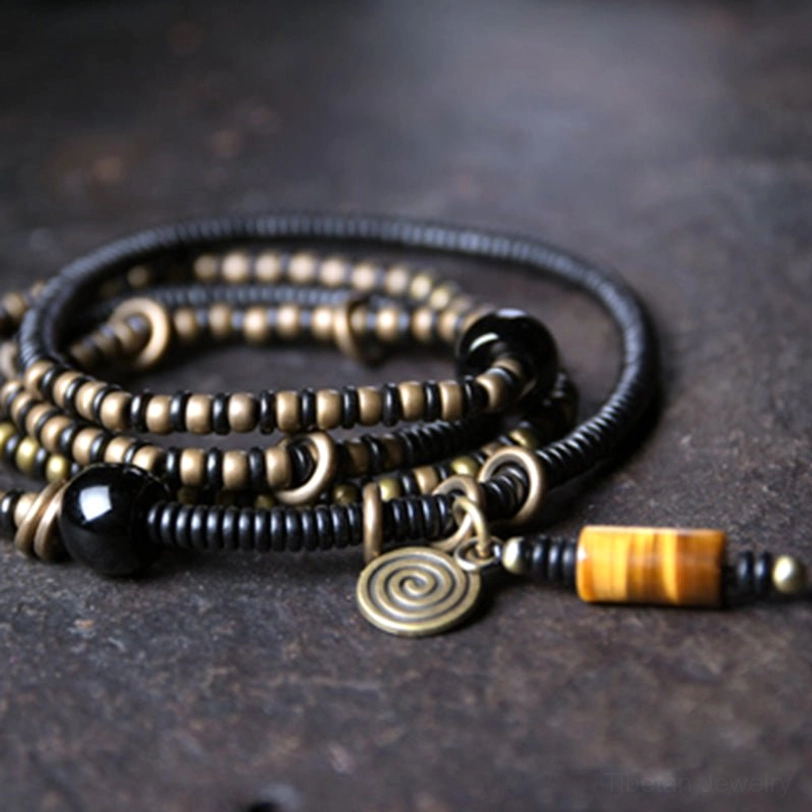 Tibetan ebony wood Dzi bead bracelet set with spiral metal charm detail, flat lay overhead view