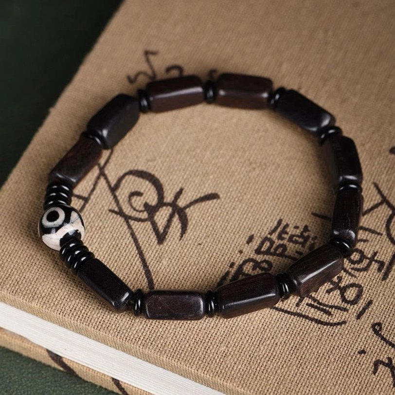 Flat lay overhead shot of Tibetan balance bracelet with two-eye Dzi on vintage book background