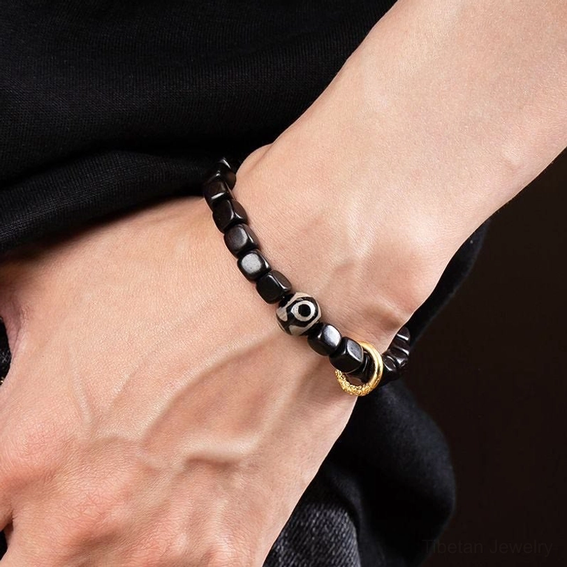 Tibetan ebony dzi bead bracelet worn on two wrists showing protective amulet in action