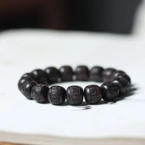 Tibetan ebony wood Om Mani Padme Hum engraved prayer bracelet with mantra beads on book flat lay