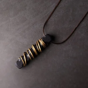 Ebony wood Tibetan necklace pendant shot at oblique angle, highlighting the brass wire coils and brown wax cord construction