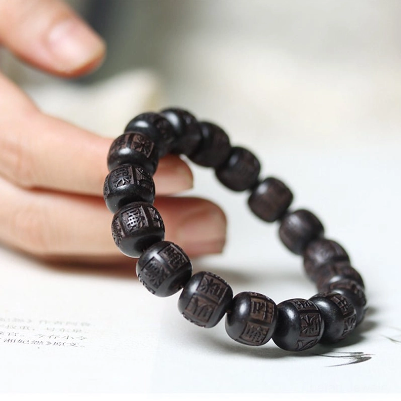 Ebony wood Tibetan prayer bracelet in closed loop on book showing complete mantra strand