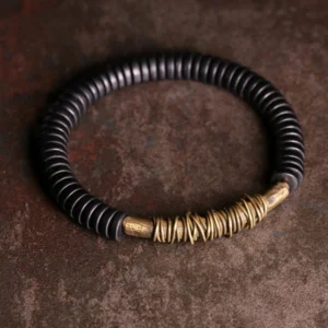 Tibetan ebony wood copper bracelet full view, flat lay on vintage textured surface showing minimalist design with black disc beads and aged copper accents