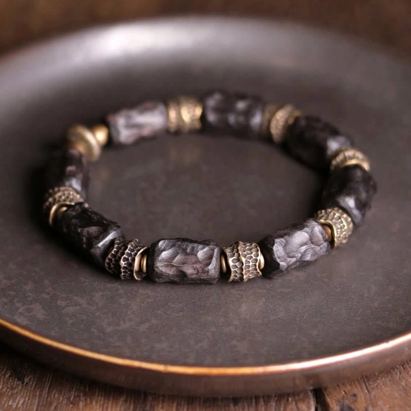 Tibetan ebony wood copper bracelet overhead display showing full circular bead arrangement with dark wood beads and vintage bronze carved spacers on metal tray