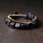 Tibetan ebony wood and copper double wrap bracelet displayed from top-down angle, showing two-layer beaded design with black wood beads and bronze metal coils on dark rustic surface