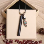 Tibetan ebony wood dzi bead necklace with black wax cord in gift presentation on wooden surface with decorative elements