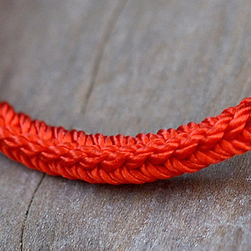 Detailed side close-up of tibetan eight-thread braided red rope texture showing tight interlocking weave pattern