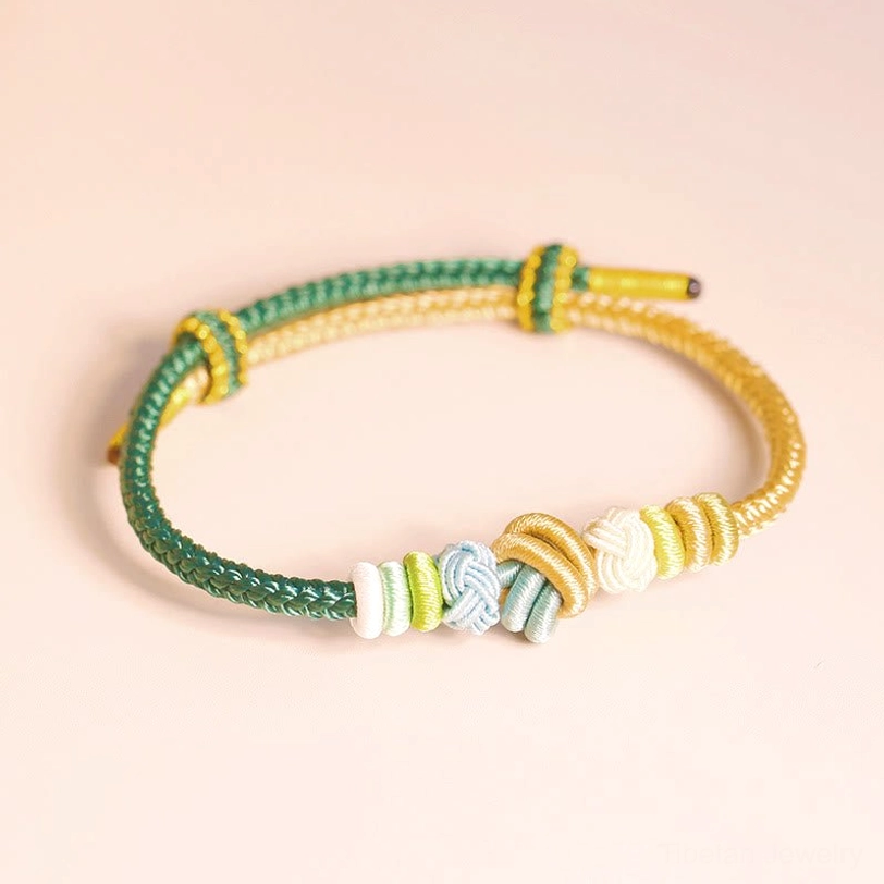 Tibetan peace knot bracelet in earthy green and gold tones with coiled braided knot design, flat lay photography