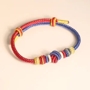 Eight-thread Tibetan blessing bracelet flat lay showing intricate braided knot work in red blue and gold colorway
