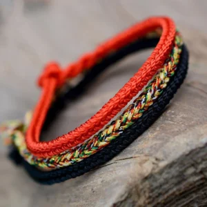Tibetan eight-thread braided peace knot bracelet in multicolor red and black woven strands, overhead view on wooden surface