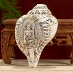 Handcarved Tibetan engraved conch shell Buddha decoration with seated figure and cloud patterns on pale cream shankha