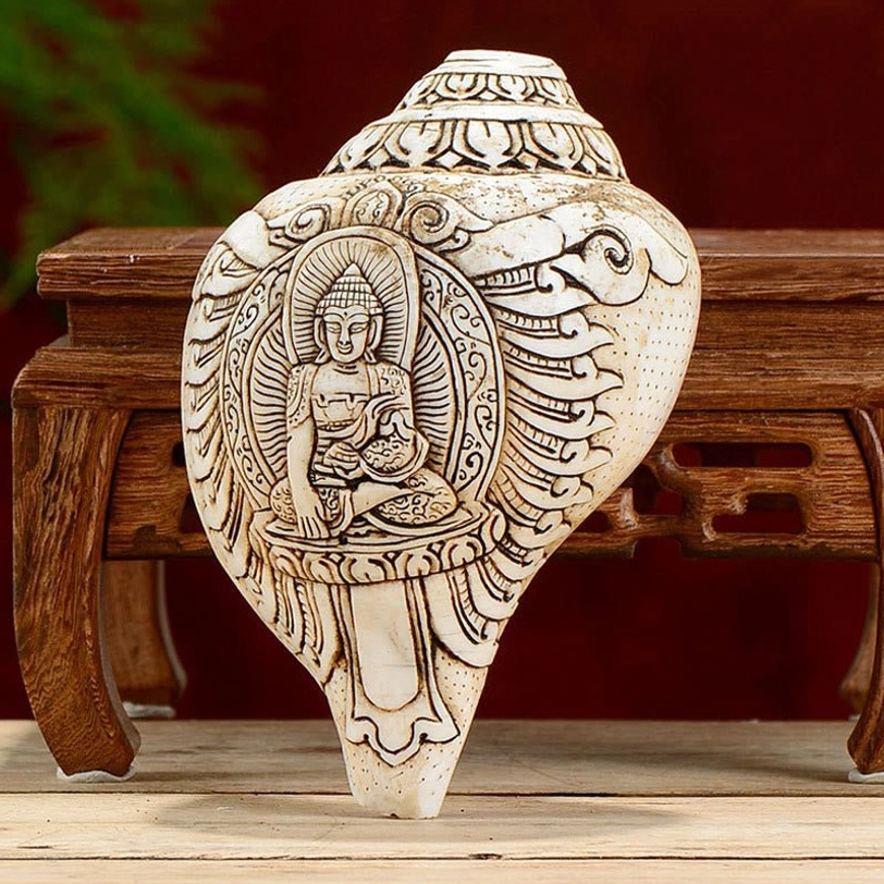 Handcarved Tibetan engraved conch shell Buddha decoration with seated figure and cloud patterns on pale cream shankha