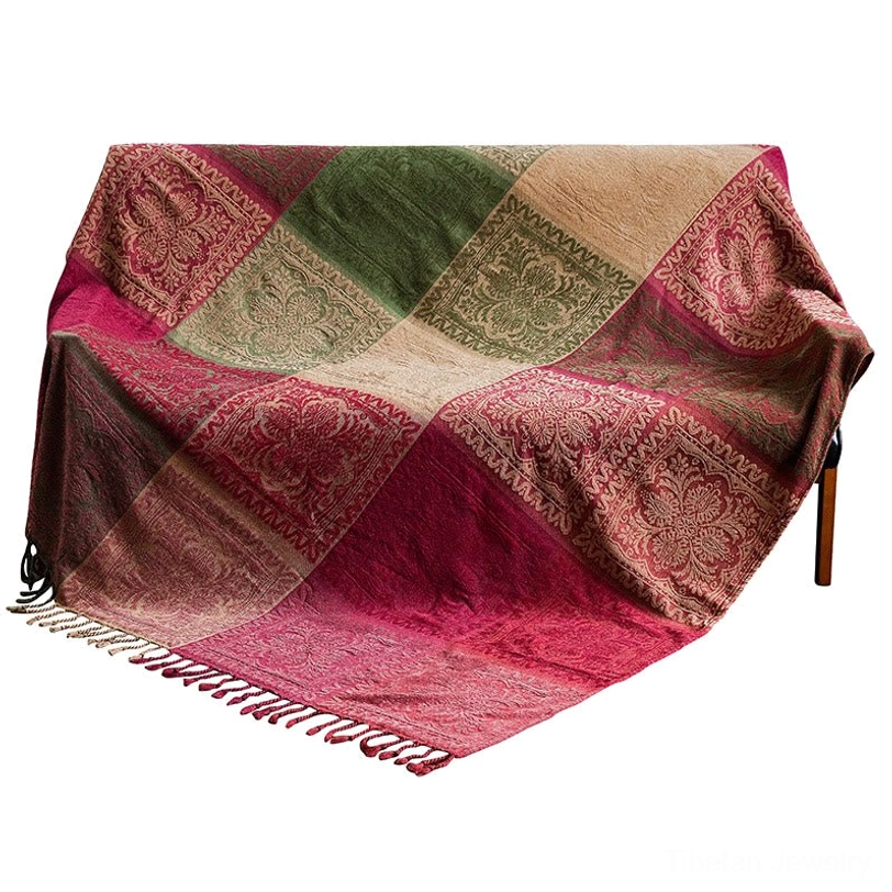 Tibetan ethnic woven throw blanket with braided tassel bottom trim and patchwork floral design, draped as upholstery in home interior