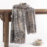 Tibetan ethnic paisley shawl in rosy brown displayed on wooden bench with coffee cup - vintage floral print scarf wrap